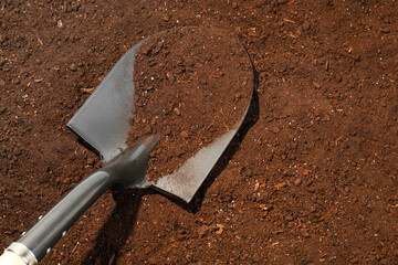 Metal shovel on fertile soil, space for text. Gardening tool
