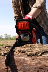 Fototapeta premium Man sawing wooden log outdoors, closeup view