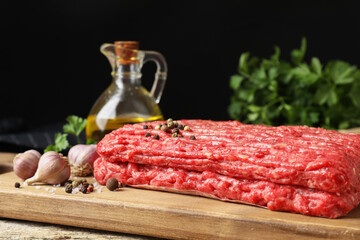Raw ground meat, spices, parsley and oil on table, closeup
