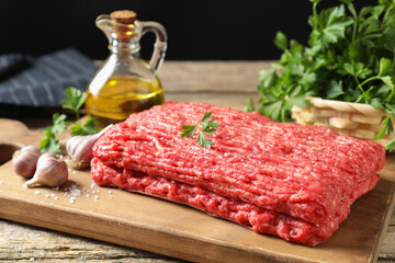 Raw ground meat, garlic, oil and parsley on wooden table