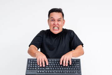 A middle aged man is angry and irate while typing furiously on his keyboard. Toxic online behavior...
