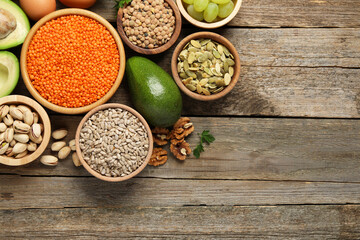 Different products high in natural fats on wooden table, flat lay. Space for text