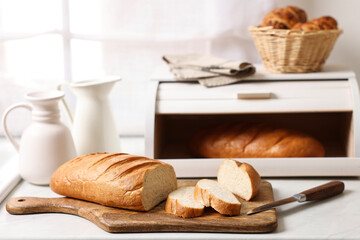 Wooden bread basket with freshly baked loaves on white marble table in kitchen