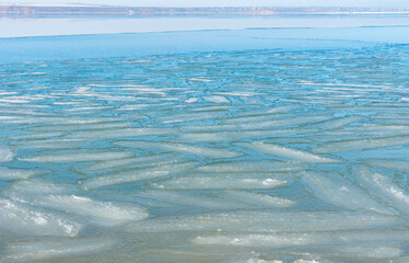 Ice floating near the shore in the form of oblong ice floes, rolled around by waves and a storm in the Tiligul estuary