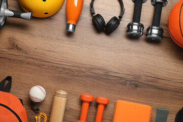 Frame made of different sports equipment on wooden table, flat lay. Space for text