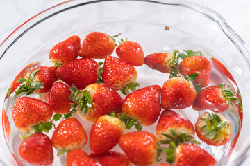Preparing Strawberries in a Glass Mixing Bowl with Water