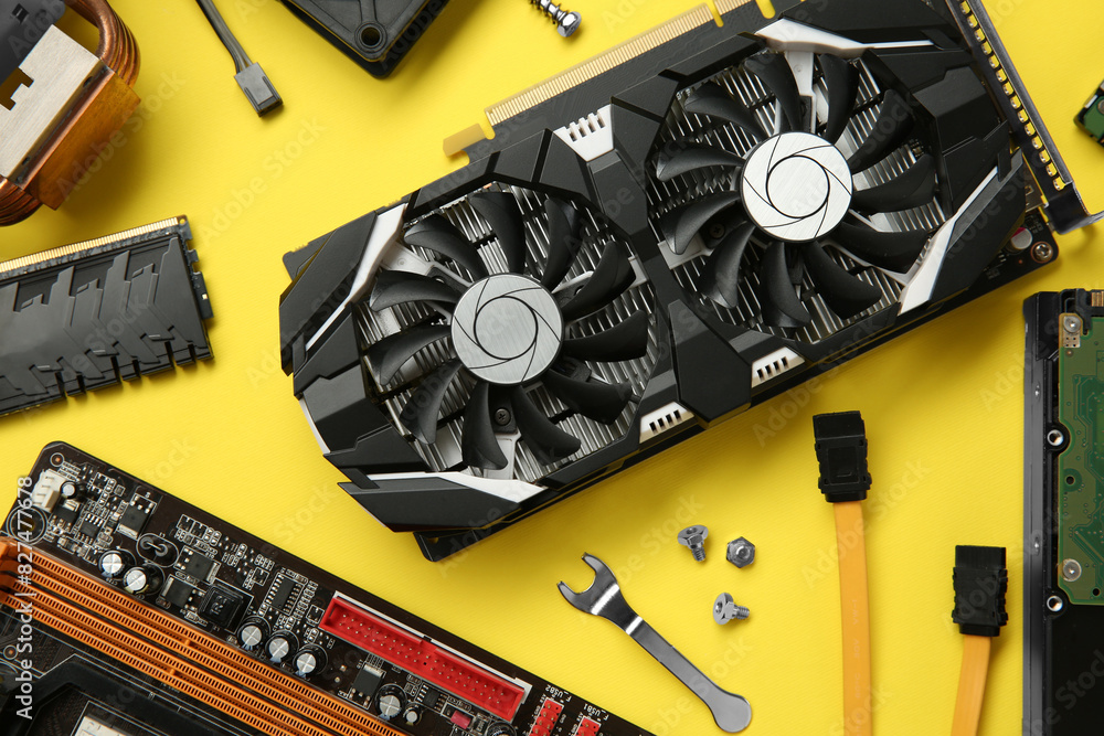 Poster graphics card and other computer hardware on yellow background, flat lay
