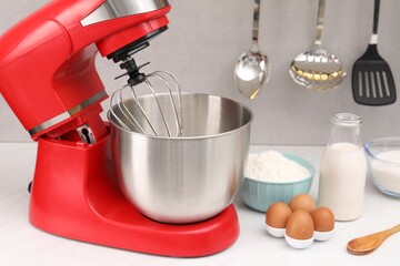 Modern red stand mixer and products on white table in kitchen