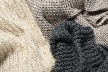 Stylish knitted scarfs as background, top view