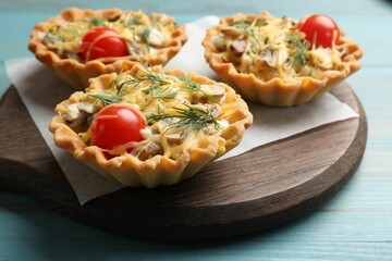 Tasty tartlets with cheese, tomatoes, mushrooms and dill on turquoise wooden table, closeup