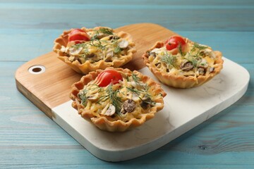 Tasty tartlets with cheese, tomatoes, mushrooms and dill on turquoise wooden table, closeup