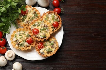 Tasty tartlets with cheese, tomatoes, mushrooms and dill on wooden table, flat lay. Space for text