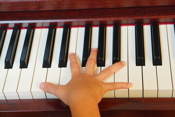 ピアノの鍵盤の上に広げた子供の手