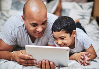 Father, son and tablet in bedroom for bonding with smile, home and online streaming. Caring, parent and trust with laugh for video in house or gaming together in morning for development in Germany.