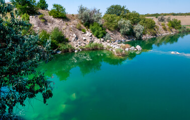 Obraz premium View of the flooded granite quarry with turquoise clear water, Ukraine