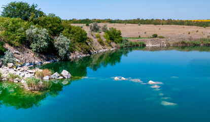Obraz premium View of the flooded granite quarry with turquoise clear water, Ukraine