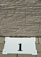 House number plate next to the wall of a building
