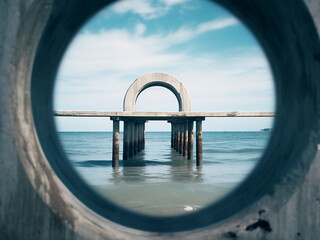 Through the lens, a concrete pier, sea, and sky offer an inverted view, symbolizing summer