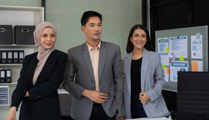 Business team smiling and confident standing in front of bright desk.