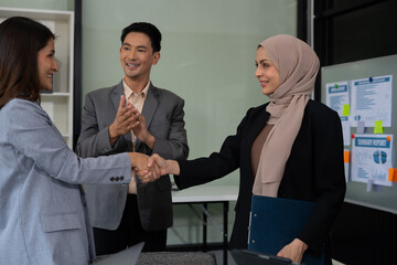 Happy businessman and businesswoman shaking hands at group board meeting. Professional business...