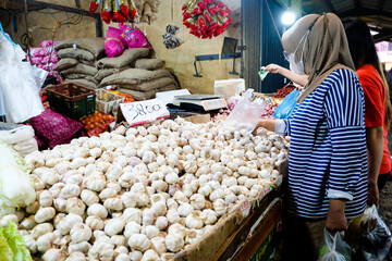 Consumers buy garlic at the traditional market in Pontianak City, Indonesia. Pile of garlic on a basket, displayed in traditional market stall.