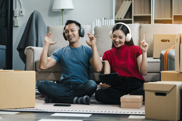 Young couple relaxing sitting on the sofa using the computer laptop around cardboard boxes, very...