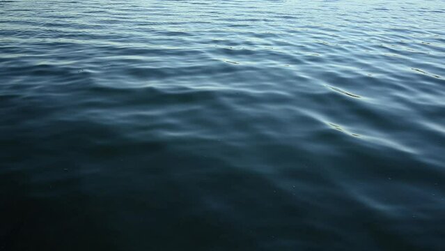 Looking down at small waves making interesting patterns on the surface of the water in a small lake.  The moving water creates many shades of blue.
