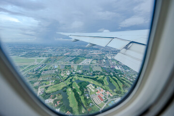 Fototapeta premium Gaze out of an airplane window to witness the harmonious blend of the airplane wing against the backdrop of the city and sky.