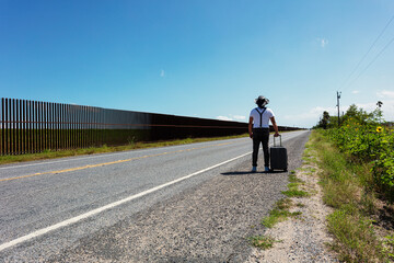 Obraz premium person with a gray suitcase next to the wall in Brownsville, Texas