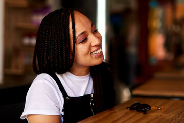 Coffee shop, happy and black woman in cafe at counter for drink, caffeine beverage and cappuccino. Restaurant, relax and face of young person with smile, confidence and diner for breakfast or lunch