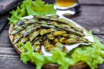Wooden Plate Topped With Lettuce Covered in Sauce
