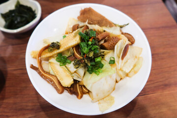 close up of Taiwanese Taiwanese braised dish with pig ear, pork, pig stomach, spring onion and cabbage on a white plate