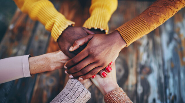 Diverse group of people stacking hands in unity over rustic wood