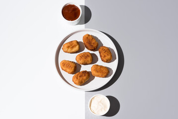 Plato de croquetas fritas con salsa de tomate y mayonesa aperitivo sobre fondo gris y blanco. Vista superior