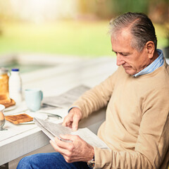Mature, businessman and newspaper for reading in backyard with breakfast and information. Stock...