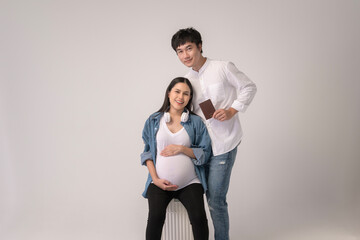 Portrait of Beautiful pregnant woman and husband traveling over white background studio, insurance and maternity concept