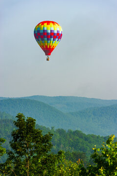 A colorful hot air balloon in a hazy blue sky over the mountains of North Georgia