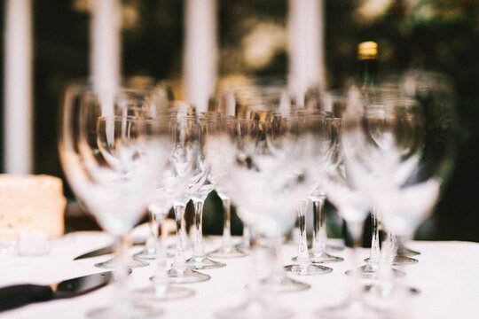 extreme shallow focus shot of rows of crystal wine glasses arranged on a white table at a wedding