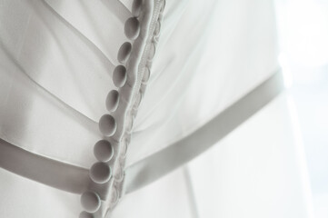 Softly backlit detail of the back of a sheer wedding dress