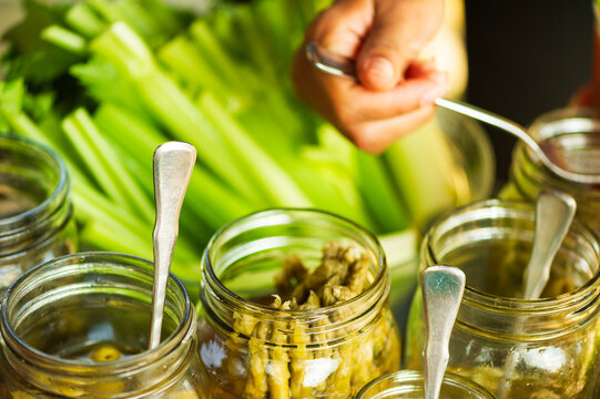 Closeup of a hand serving from a stack of celery, pickled asparagus, and other bloody mary ingredients at a wedding