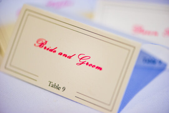 A paper place card reading "Bride and Groom" on a table at a wedding