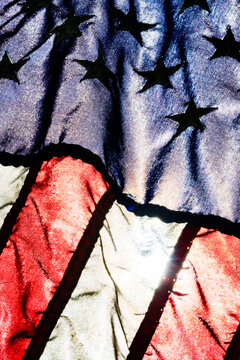 Light from a partial solar eclipse shining through a synthetic American flag, detail