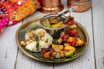 Air fried vegan barbeque  seitan and vegetables skewers served on banana leaf along with Indian pongal and sambar
