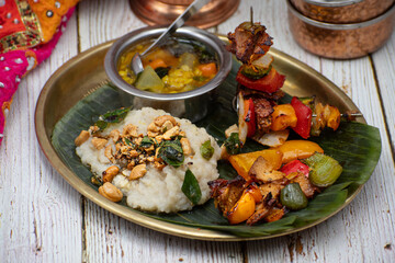 Air fried vegan barbeque  seitan and vegetables skewers served on banana leaf along with Indian pongal and sambar
