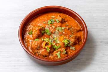 a plate of mutton curry masala gravy isolated on white wooden table from above 