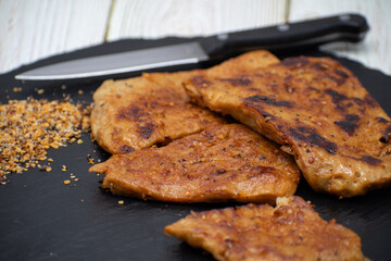 Vegan seitan schitzel slices on slate plate, cut steak style