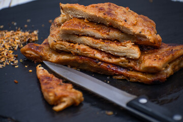 Vegan seitan schitzel slices on slate plate, cut steak style