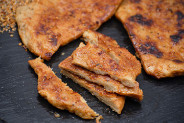 Vegan seitan schitzel slices on slate plate, cut steak style