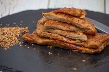 Vegan seitan schitzel slices on slate plate, cut steak style