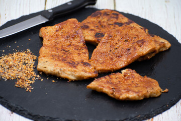 Vegan seitan schitzel slices on slate plate, cut steak style